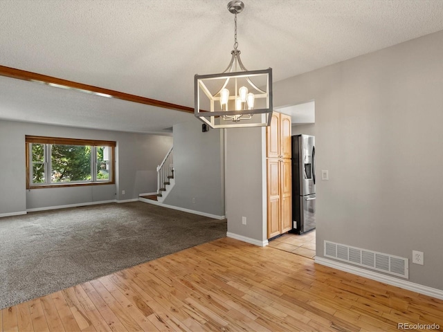 5903 S Ward St, Littleton, CO 80127 - empty room with stairs, a chandelier, light wood-type flooring, and a textured ceiling
