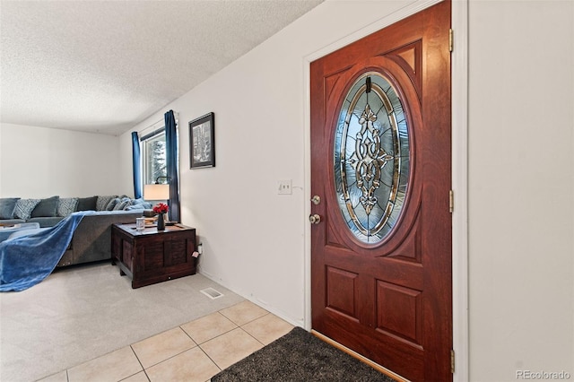 carpeted foyer entrance with a textured ceiling