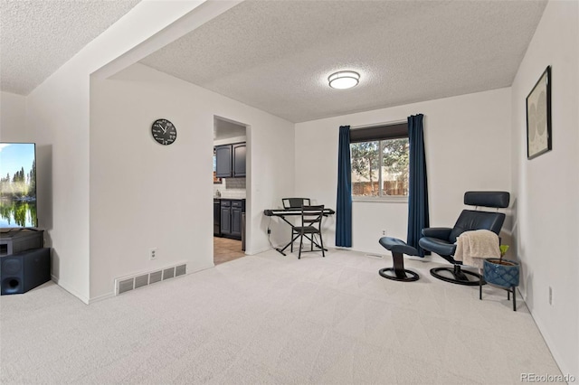 living area with light colored carpet and a textured ceiling