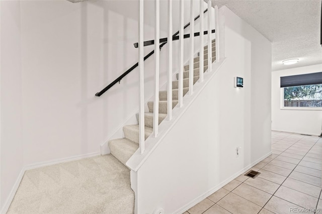 staircase featuring tile patterned floors and a textured ceiling