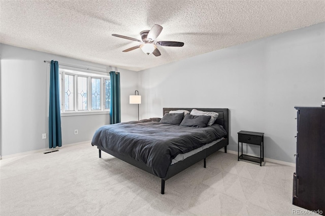 bedroom featuring light carpet, ceiling fan, and a textured ceiling