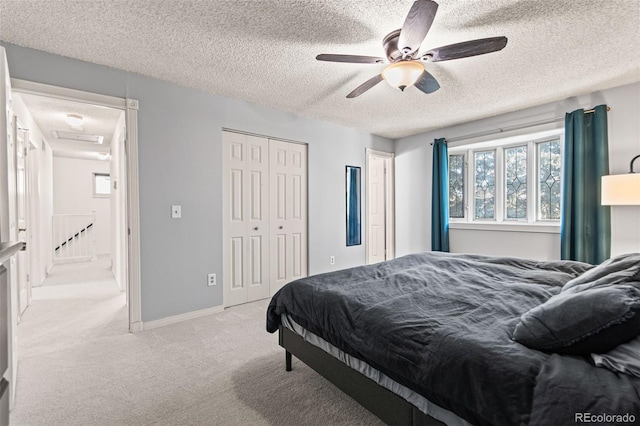 bedroom with ceiling fan, light colored carpet, a closet, and a textured ceiling