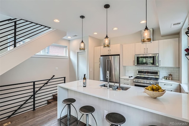 1895 York St, Denver, CO 80206 - kitchen with appliances with stainless steel finishes, a kitchen bar, wood finished floors, pendant lighting, and light countertops