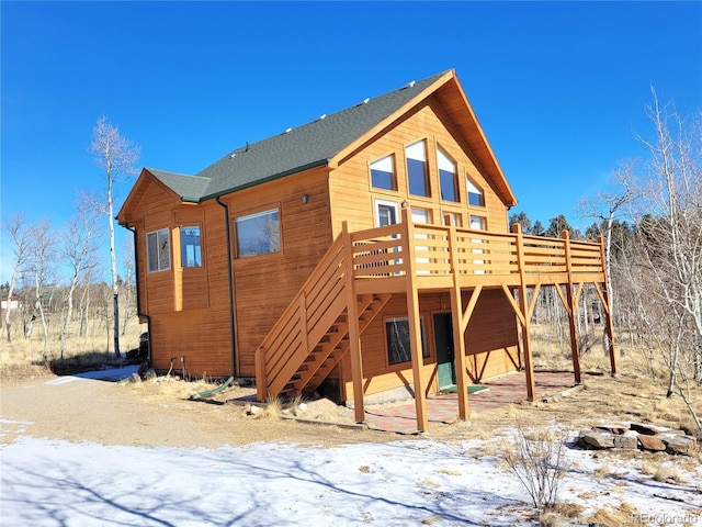 snow covered house featuring stairs and a deck