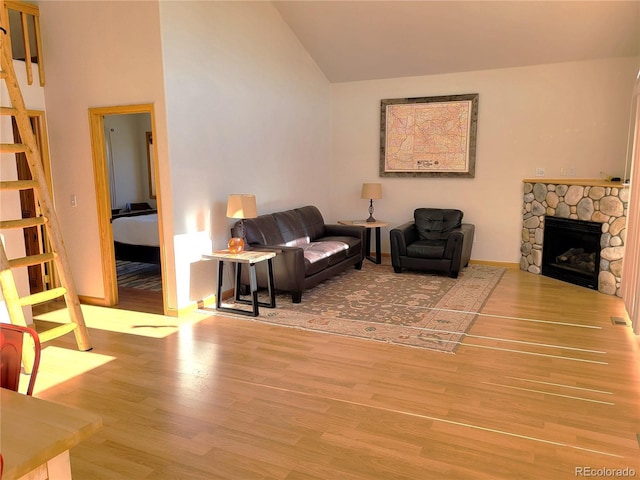 living area with a fireplace, visible vents, vaulted ceiling, wood finished floors, and stairs