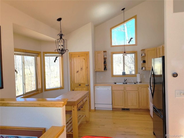 kitchen featuring light brown cabinets, white dishwasher, open shelves, and freestanding refrigerator