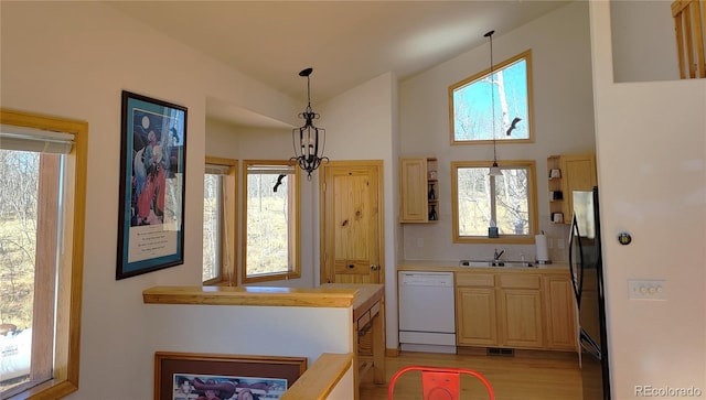 kitchen with plenty of natural light, dishwasher, vaulted ceiling, light countertops, and a sink