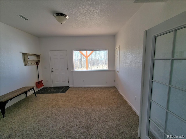 carpeted foyer entrance featuring visible vents, a textured wall, a textured ceiling, and baseboards