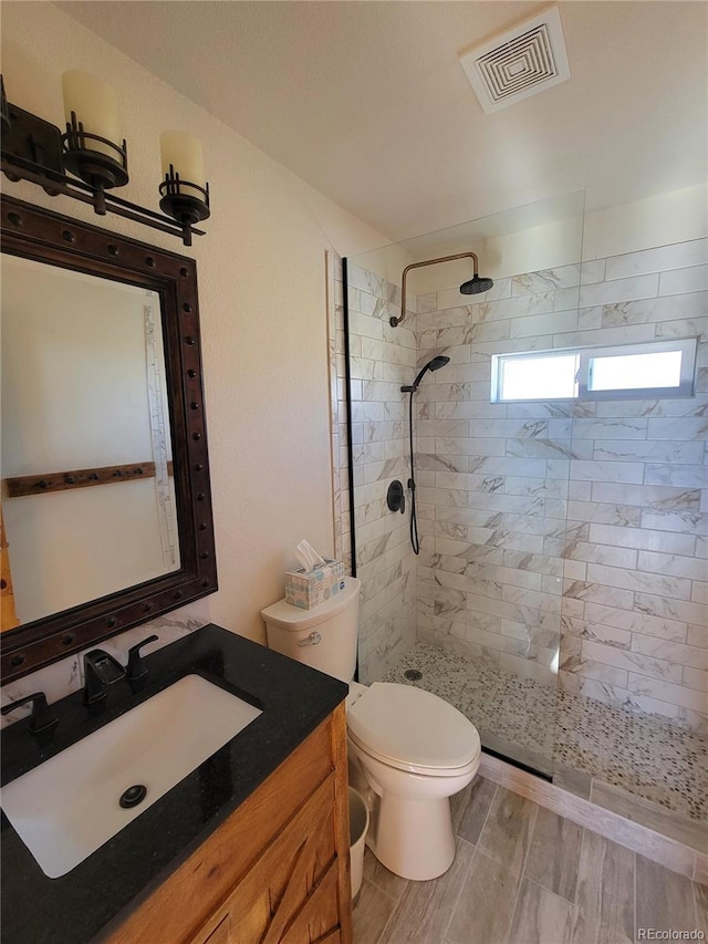 bathroom with toilet, vanity, a walk in shower, and visible vents