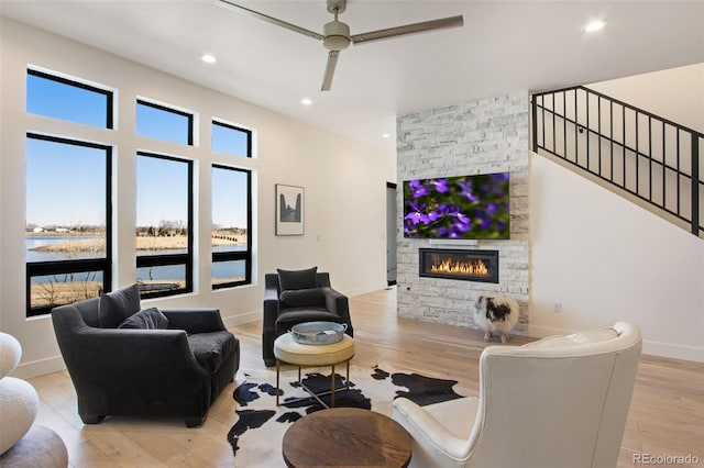 living room with a ceiling fan, baseboards, light wood finished floors, recessed lighting, and a fireplace