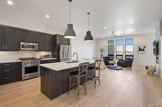 kitchen featuring a sink, stainless steel appliances, a kitchen breakfast bar, and light wood-type flooring