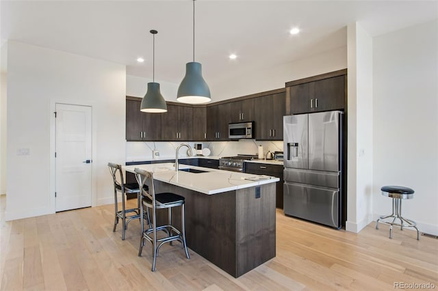 kitchen featuring dark brown cabinetry, light wood-style flooring, appliances with stainless steel finishes, and a sink