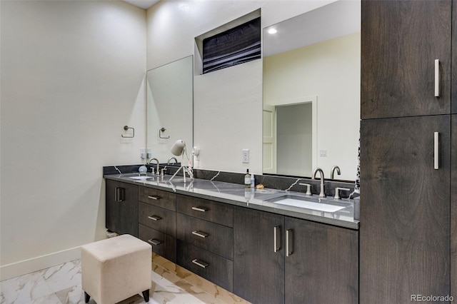 bathroom with double vanity, baseboards, marble finish floor, and a sink