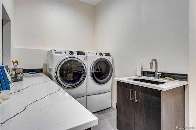 laundry room featuring washing machine and clothes dryer, light tile patterned floors, and a sink