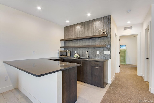 kitchen with visible vents, open shelves, stainless steel microwave, a sink, and dark brown cabinetry