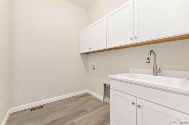 7051 S White Crow Way, Aurora, CO 80016 - clothes washing area featuring hookup for a washing machine, cabinet space, light wood-style flooring, and baseboards
