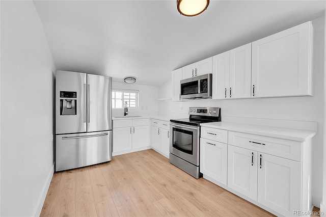 3064 S Galapago St, Englewood, CO 80110 - kitchen featuring appliances with stainless steel finishes, light wood-style floors, light countertops, white cabinetry, and a sink
