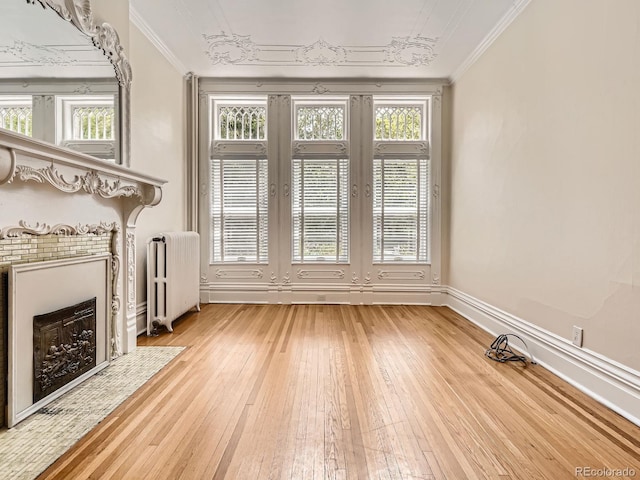 1453 Vine St, Denver, CO 80206 - unfurnished living room with radiator heating unit, light wood finished floors, crown molding, healthy amount of natural light, and baseboards