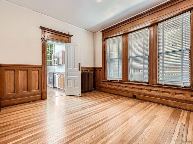 1453 Vine St, Denver, CO 80206 - spare room with radiator, light wood-style flooring, and a wainscoted wall