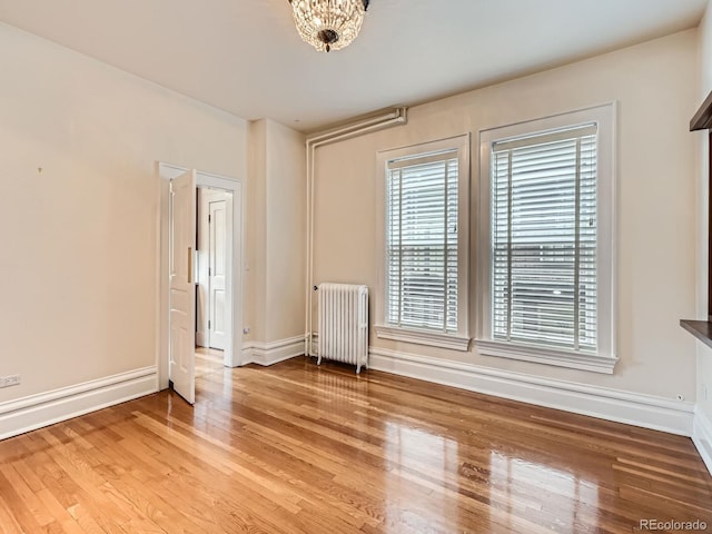 1453 Vine St, Denver, CO 80206 - unfurnished room with radiator, healthy amount of natural light, wood finished floors, and baseboards