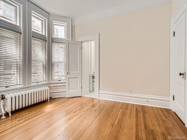 1453 Vine St, Denver, CO 80206 - unfurnished bedroom featuring radiator heating unit, light wood-type flooring, ornamental molding, and baseboards