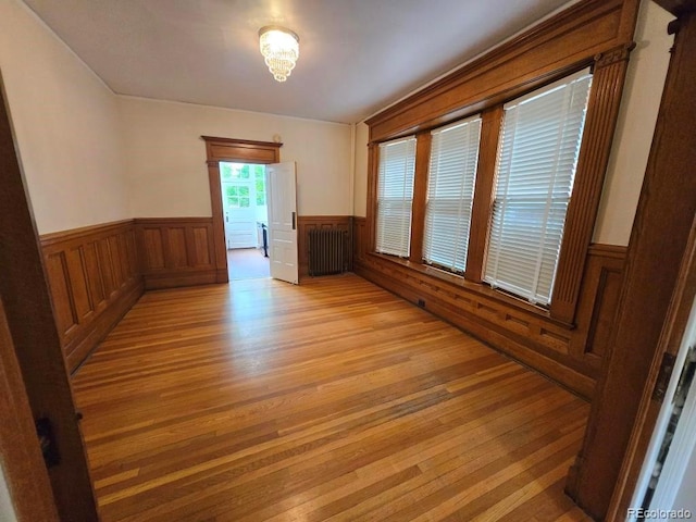 1453 Vine St, Denver, CO 80206 - unfurnished room with wainscoting, light wood finished floors, and radiator