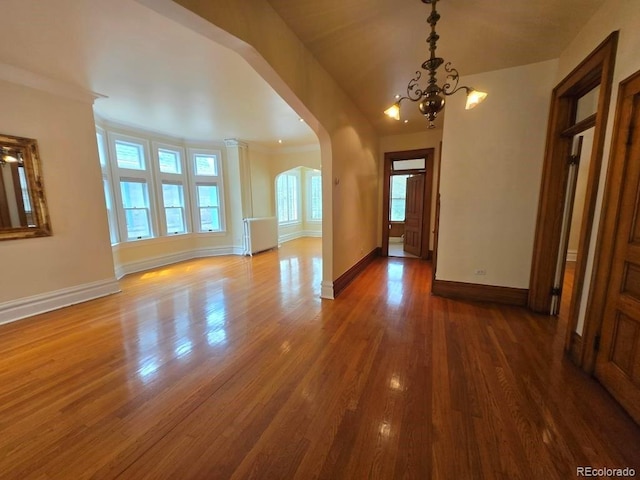 1453 Vine St, Denver, CO 80206 - unfurnished living room with a chandelier, arched walkways, wood finished floors, and ornamental molding
