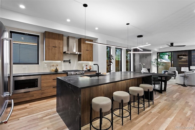 2378 S Bannock St, Denver, CO 80223 - kitchen with wall chimney range hood, dark countertops, modern cabinets, stainless steel appliances, and brown cabinetry