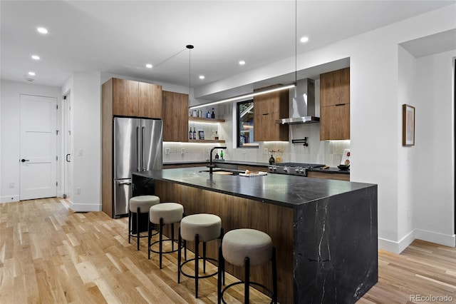 2378 S Bannock St, Denver, CO 80223 - kitchen with wall chimney range hood, high end refrigerator, modern cabinets, light wood-style flooring, and decorative backsplash