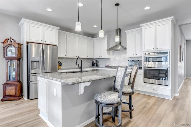 9055 Swan River St, Littleton, CO 80125 - kitchen featuring stainless steel appliances, wall chimney range hood, light wood finished floors, white cabinets, and recessed lighting