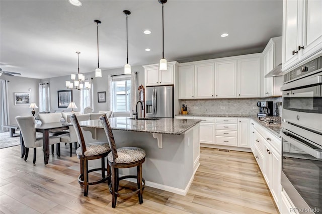 9055 Swan River St, Littleton, CO 80125 - kitchen with appliances with stainless steel finishes, light wood-style floors, light stone countertops, decorative backsplash, and recessed lighting