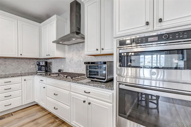 9055 Swan River St, Littleton, CO 80125 - kitchen featuring wall chimney exhaust hood, appliances with stainless steel finishes, white cabinets, stone counters, and backsplash