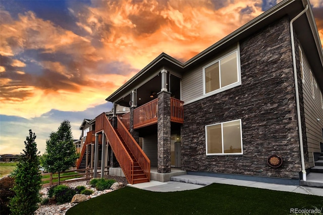 9055 Swan River St, Littleton, CO 80125 - rear view of property with stone siding, stairs, a lawn, and a deck