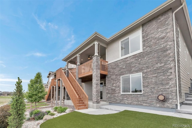 9055 Swan River St, Littleton, CO 80125 - rear view of house featuring stairs, a lawn, stone siding, and a deck