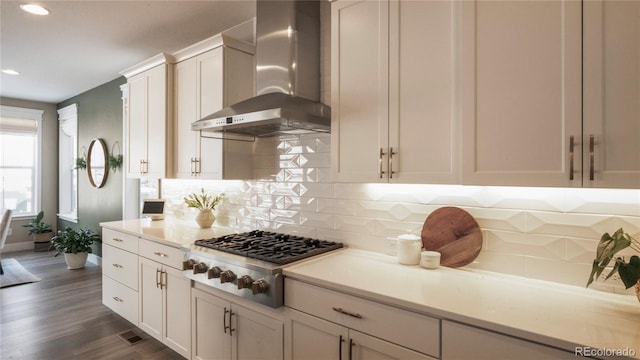 kitchen featuring wall chimney exhaust hood, dark hardwood / wood-style flooring, stainless steel gas cooktop, and white cabinets