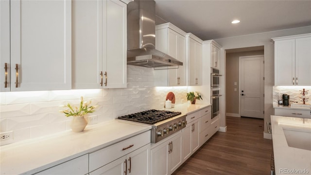 kitchen featuring white cabinetry, wall chimney range hood, dark hardwood / wood-style flooring, and stainless steel appliances