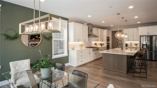 kitchen featuring pendant lighting, white cabinets, stainless steel appliances, and wall chimney range hood