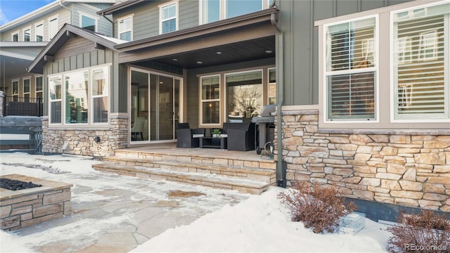 snow covered property entrance featuring a patio area