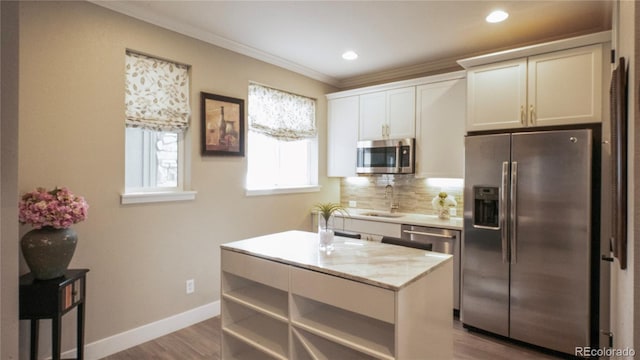 kitchen with a kitchen island, appliances with stainless steel finishes, white cabinetry, sink, and backsplash