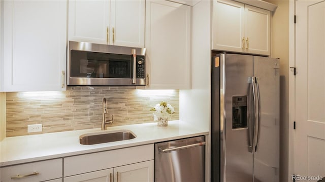 kitchen featuring stainless steel appliances, sink, white cabinets, and backsplash