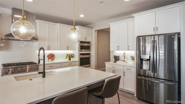 kitchen featuring hanging light fixtures, white cabinetry, appliances with stainless steel finishes, and a breakfast bar