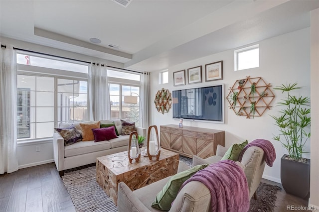 living room with baseboards, wood finished floors, visible vents, and a healthy amount of sunlight