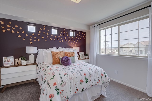 carpeted bedroom with an accent wall and baseboards