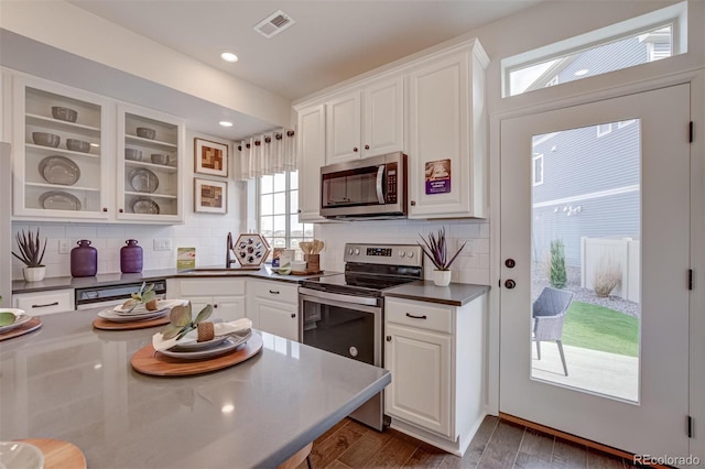 kitchen with dark countertops, white cabinetry, stainless steel appliances, and decorative backsplash