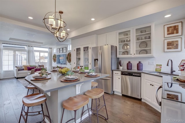 kitchen with appliances with stainless steel finishes, dark wood-type flooring, a sink, and a kitchen breakfast bar