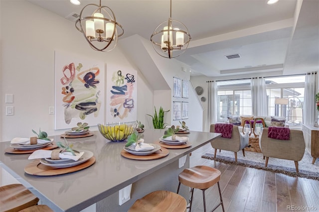 dining room featuring visible vents, hardwood / wood-style floors, a tray ceiling, a chandelier, and recessed lighting