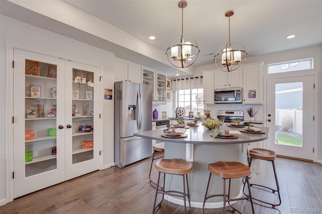 kitchen featuring glass insert cabinets, white cabinetry, stainless steel appliances, and wood finished floors