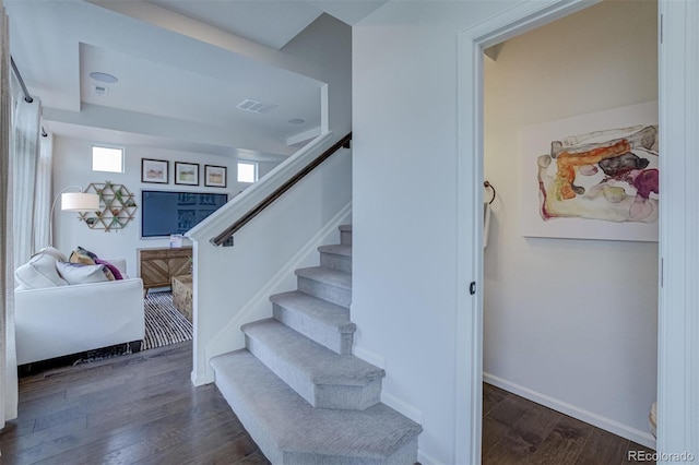 stairway featuring wood finished floors, visible vents, and baseboards