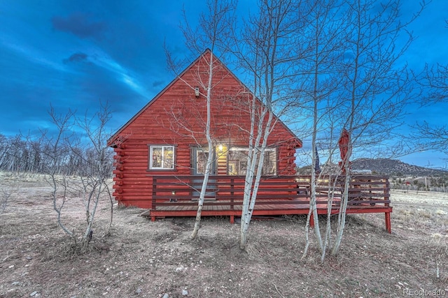 back of house featuring log exterior and a wooden deck