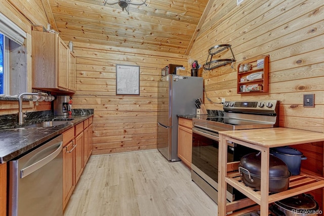 kitchen with wood walls, stainless steel appliances, lofted ceiling, and a sink